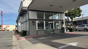 A modern building with a glass entrance, a no parking sign, and a Speedway sign in the background. - Studio 6 Corona, CA - West (Corona)