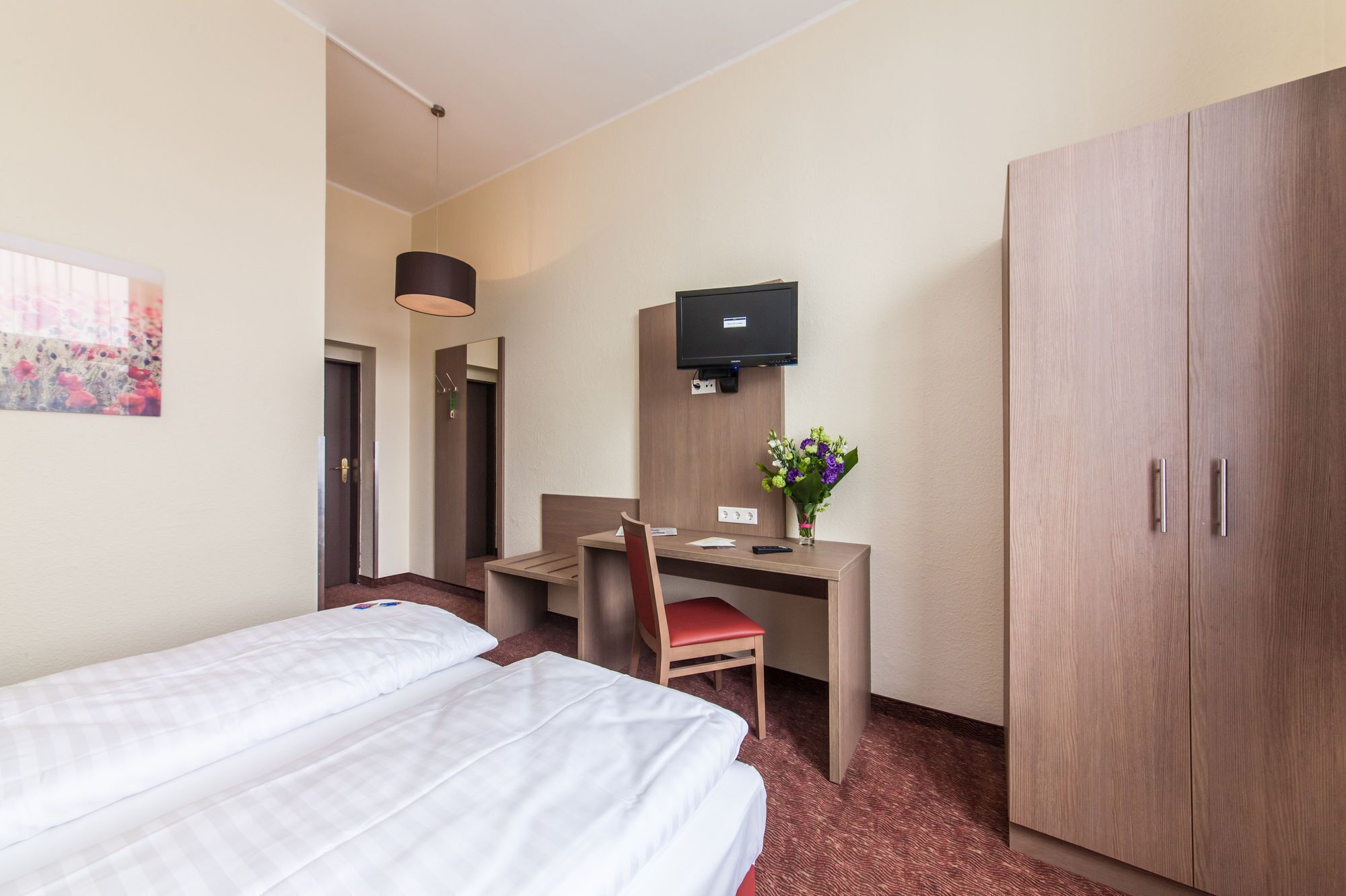 Une chambre d’hôtel équipée d’un lit, d’un bureau, d’une chaise, d’une télévision et d’une armoire.
