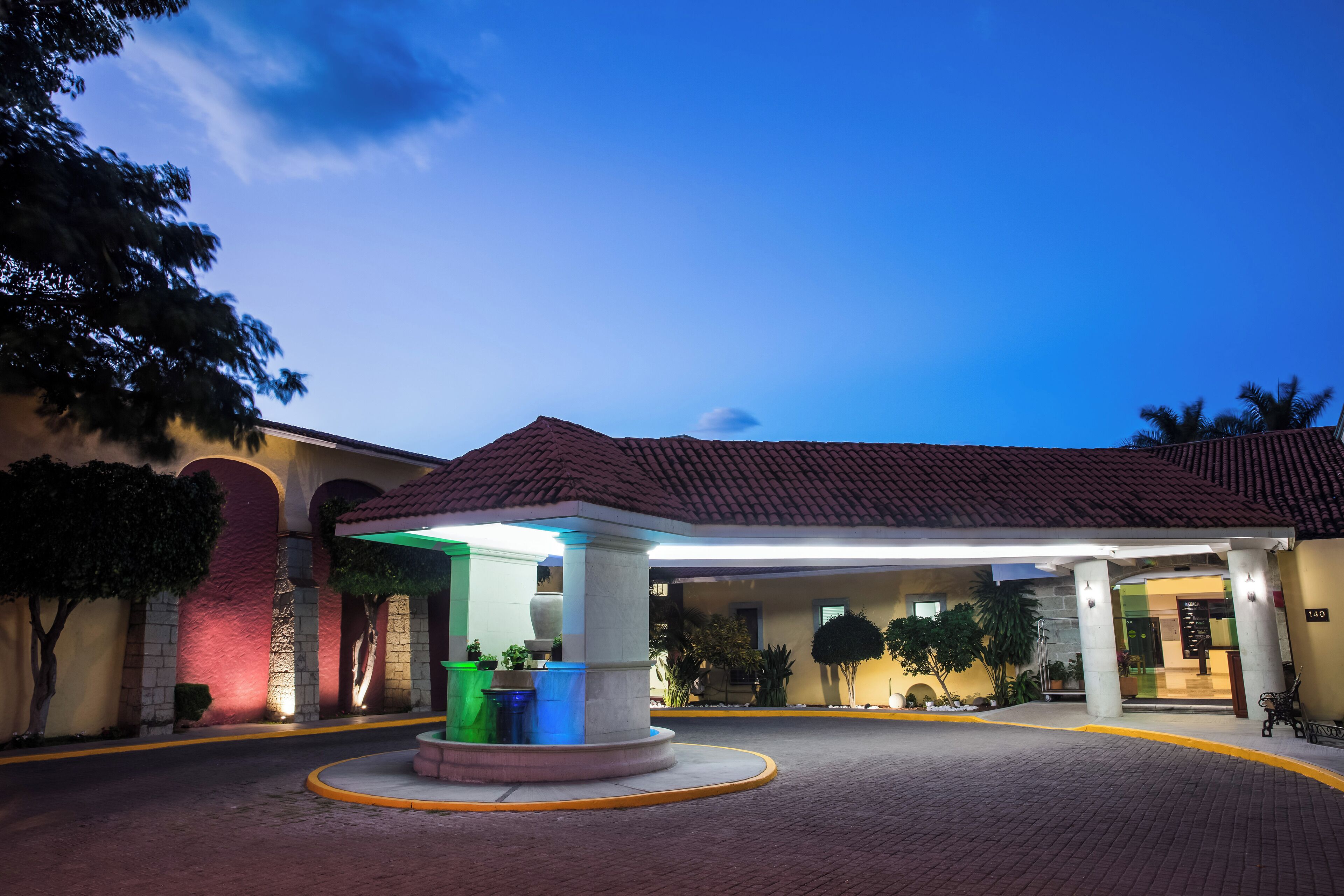 Entrada de hotel con un patio cubierto, una fuente y un jardín bien cuidado.