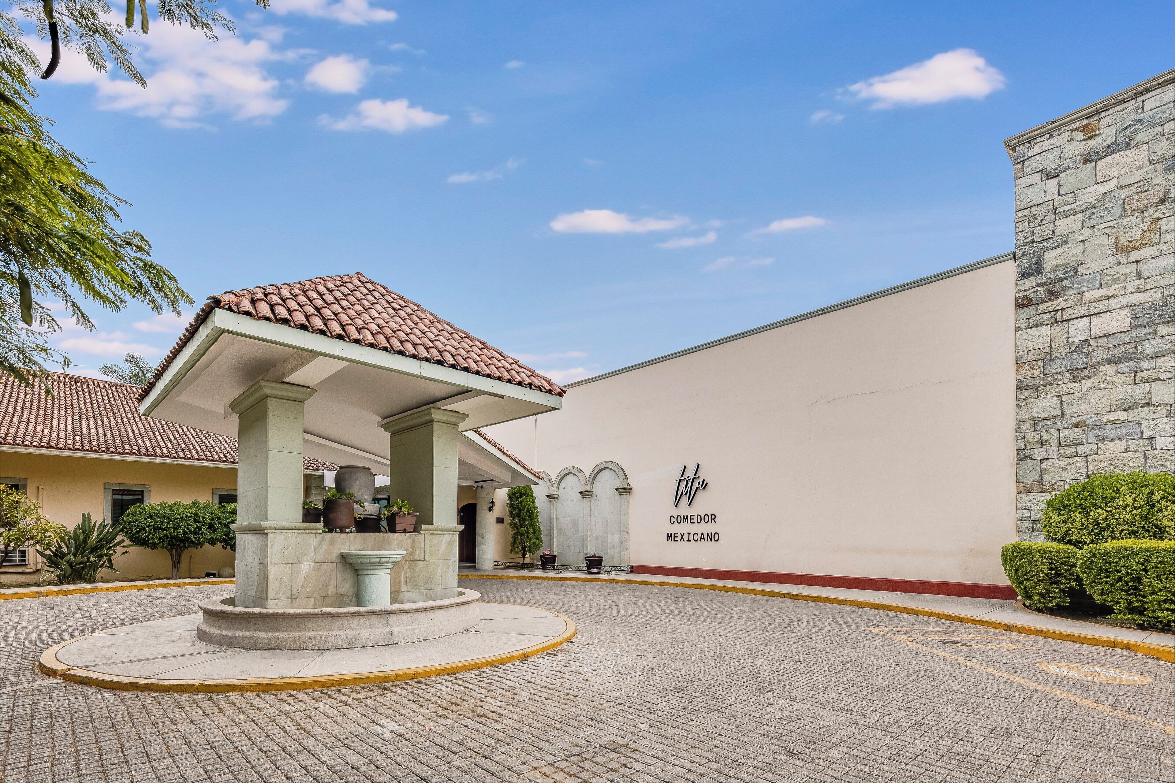 A courtyard with a tiled roof structure, a stone wall, and a sign reading 'COMEDOR MEXICANO'.