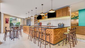 A modern bar area with a central island, bar stools, pendant lighting, and a herringbone-patterned backsplash. - Fiesta Inn Oaxaca (Oaxaca)