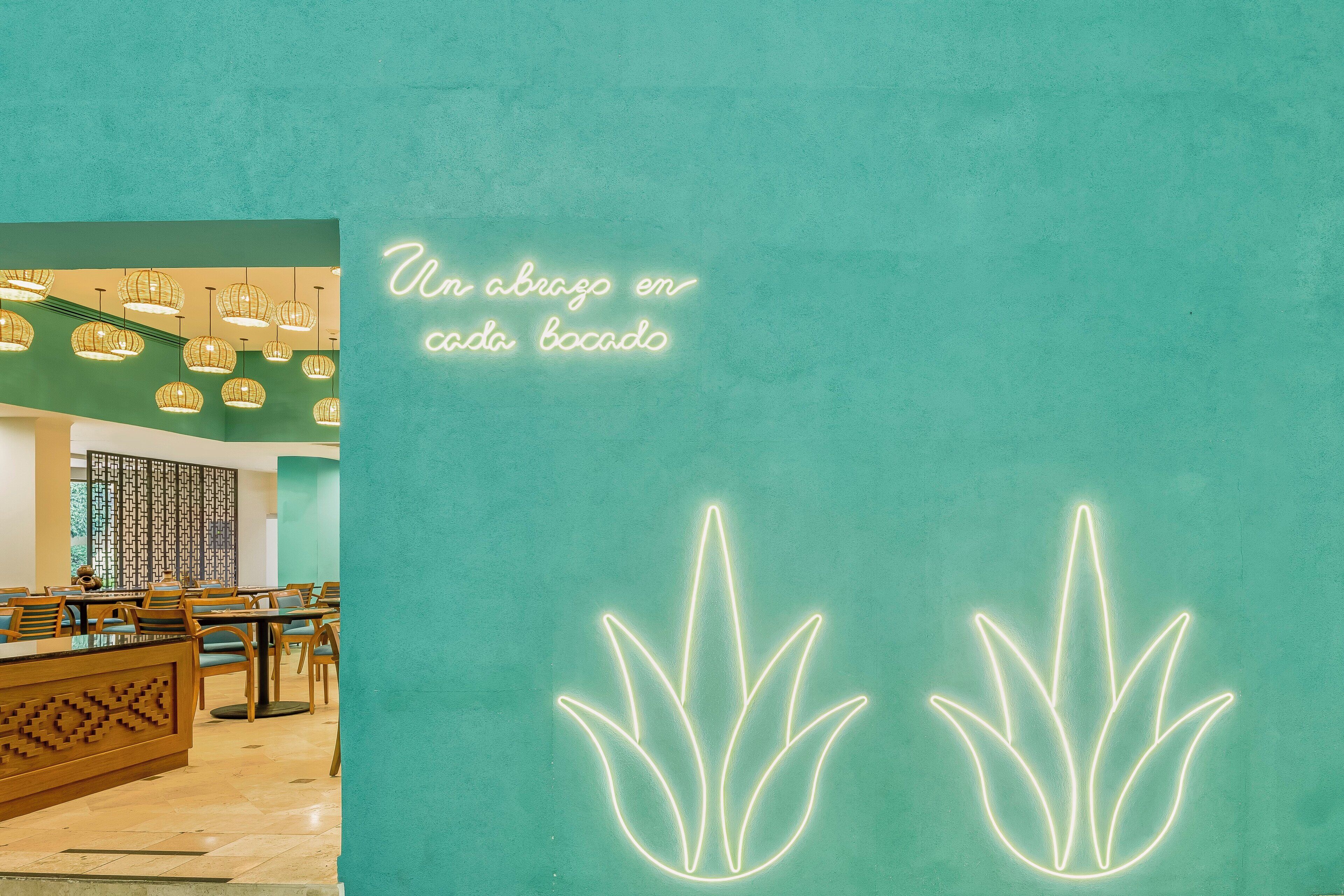 A restaurant interior with a teal color scheme, wooden furniture, and hanging light fixtures.