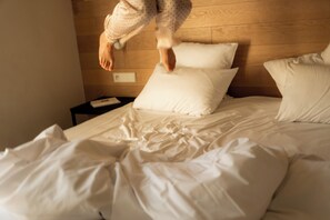Ein Bett mit weißer Bettwäsche und einem Holz-Kopfteil.