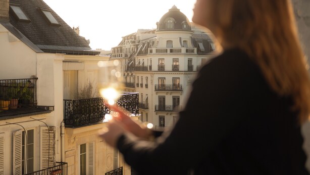 Una persona contempla un edifici amb nombroses finestres i balcons des d'un balcó.