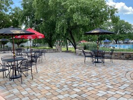 An outdoor patio area with brick flooring and metal tables and chairs.