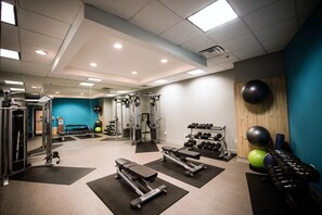 A gym with exercise equipment, weights, and a mirror.