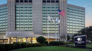 Un hotel DoubleTree by Hilton con fachada moderna, varias banderas y un césped cuidado.