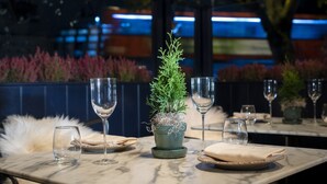 A dining table with a potted plant, wine glasses, and plates set for a meal. - InterContinental London Park Lane by IHG (London)