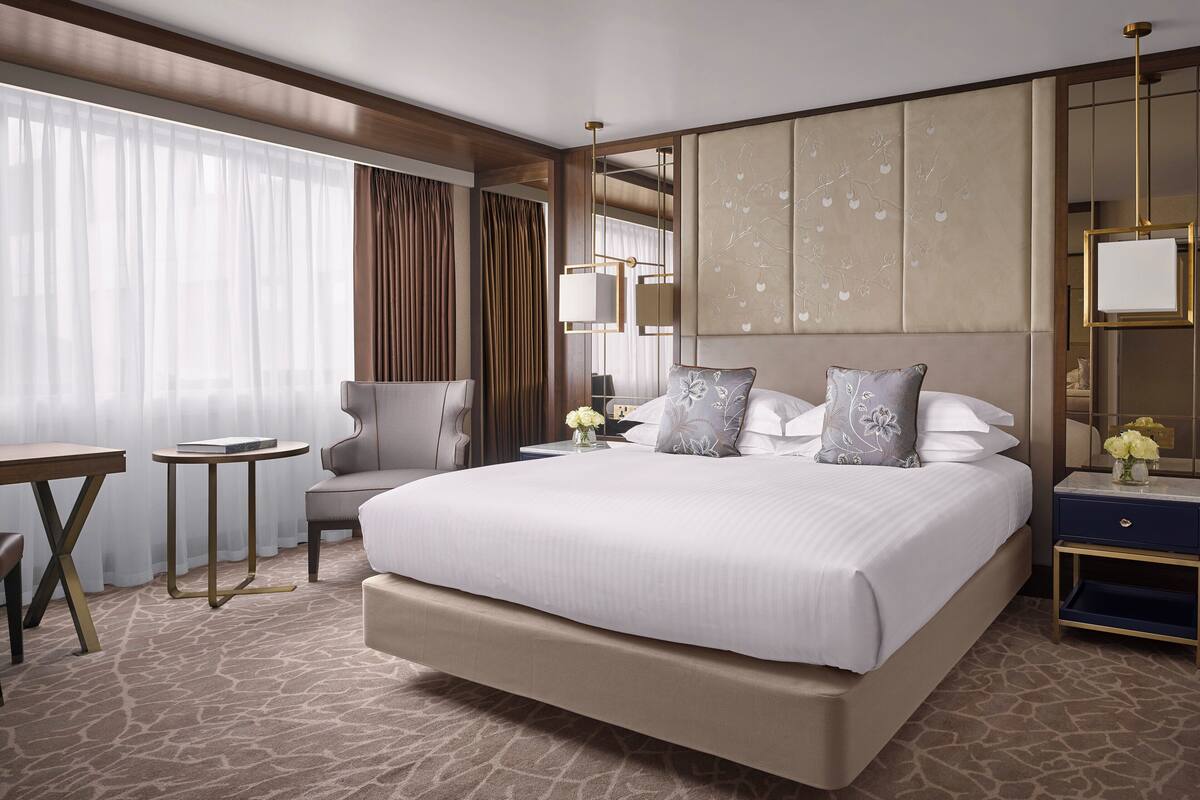A spacious hotel room with a large bed, a desk, and a chair.
