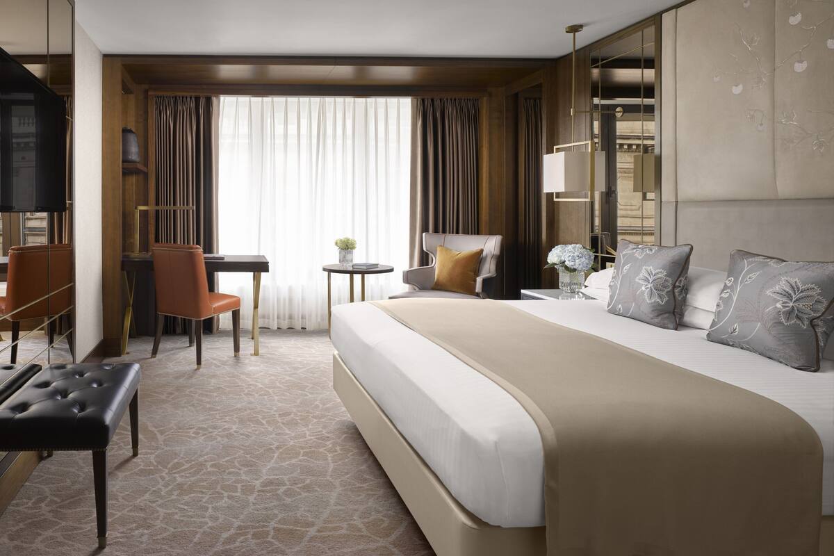 A hotel room with a large bed, a desk, a chair, and a television.