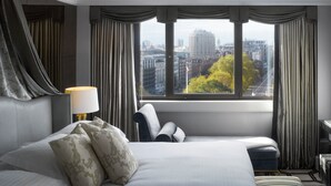 A hotel room with a large bed, a desk, and a view of a cityscape through a window with curtains. - InterContinental London Park Lane by IHG (London)