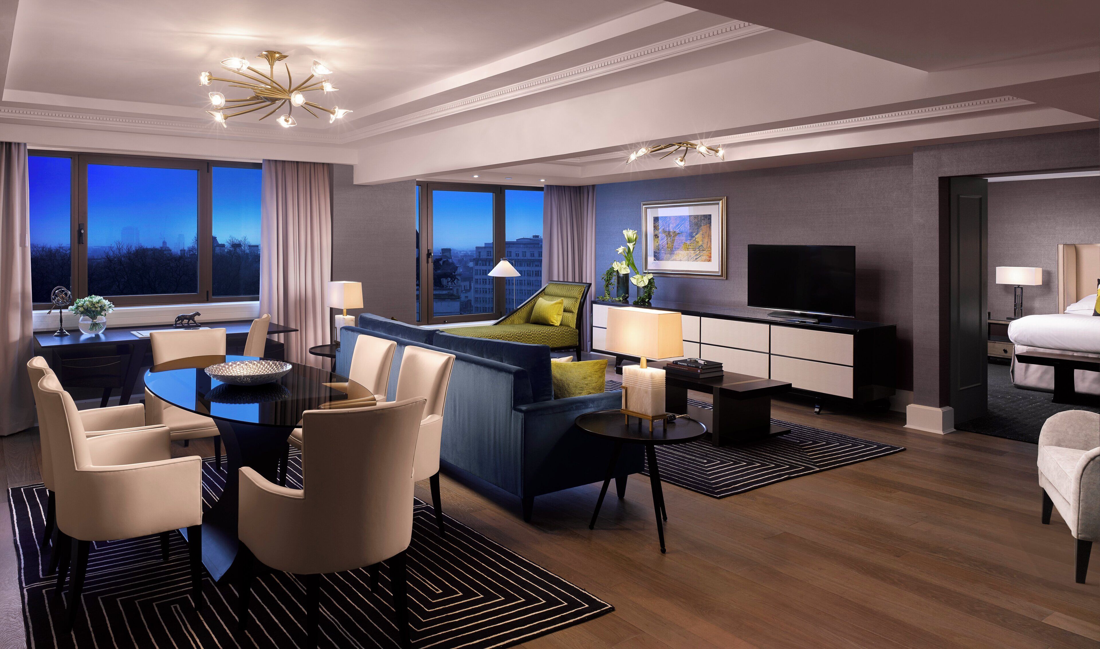 Una habitación de hotel moderna con zona de estar, cama, televisor y vistas a la ciudad.