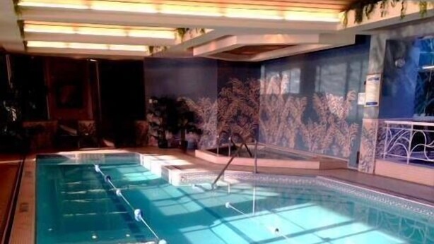 A swimming pool with multiple lanes, a lounge area with seating, and a mural on the wall. - Clarion Hotel & Suites Riverfront (Oswego)