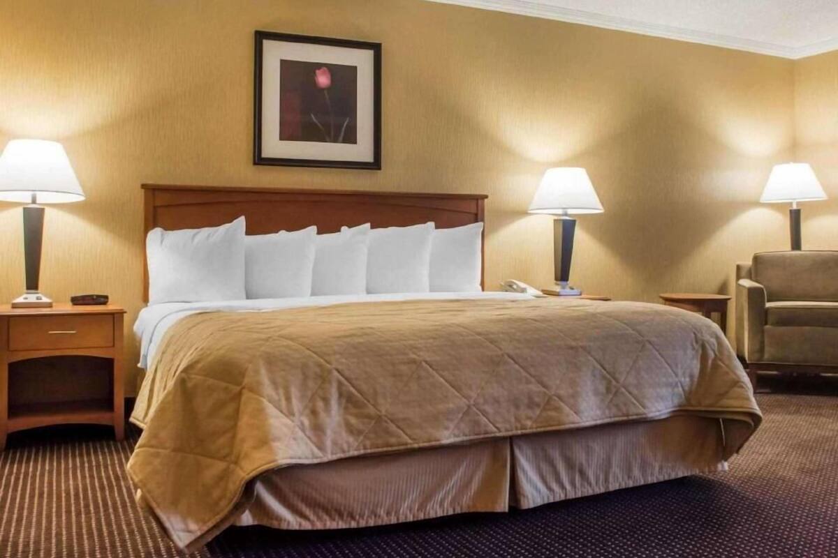 A hotel room with a large bed, two bedside tables, a chair, and a framed picture on the wall.