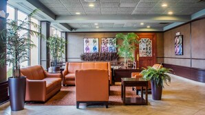 A lobby with leather sofas, a coffee table, and potted plants. - Clarion Hotel & Suites Riverfront (Oswego)