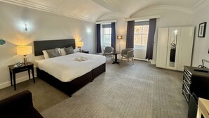 A hotel room with a large bed, two bedside tables with lamps, a desk with a chair, a wardrobe, and a window with curtains. - Carlisle Station Hotel, Sure Hotel Collection by BW (Carlisle)
