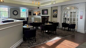 A hotel lobby with a high ceiling, decorative ceiling panels, and a patterned carpet. There are several tables and chairs arranged for guests. - Carlisle Station Hotel, Sure Hotel Collection by BW (Carlisle)