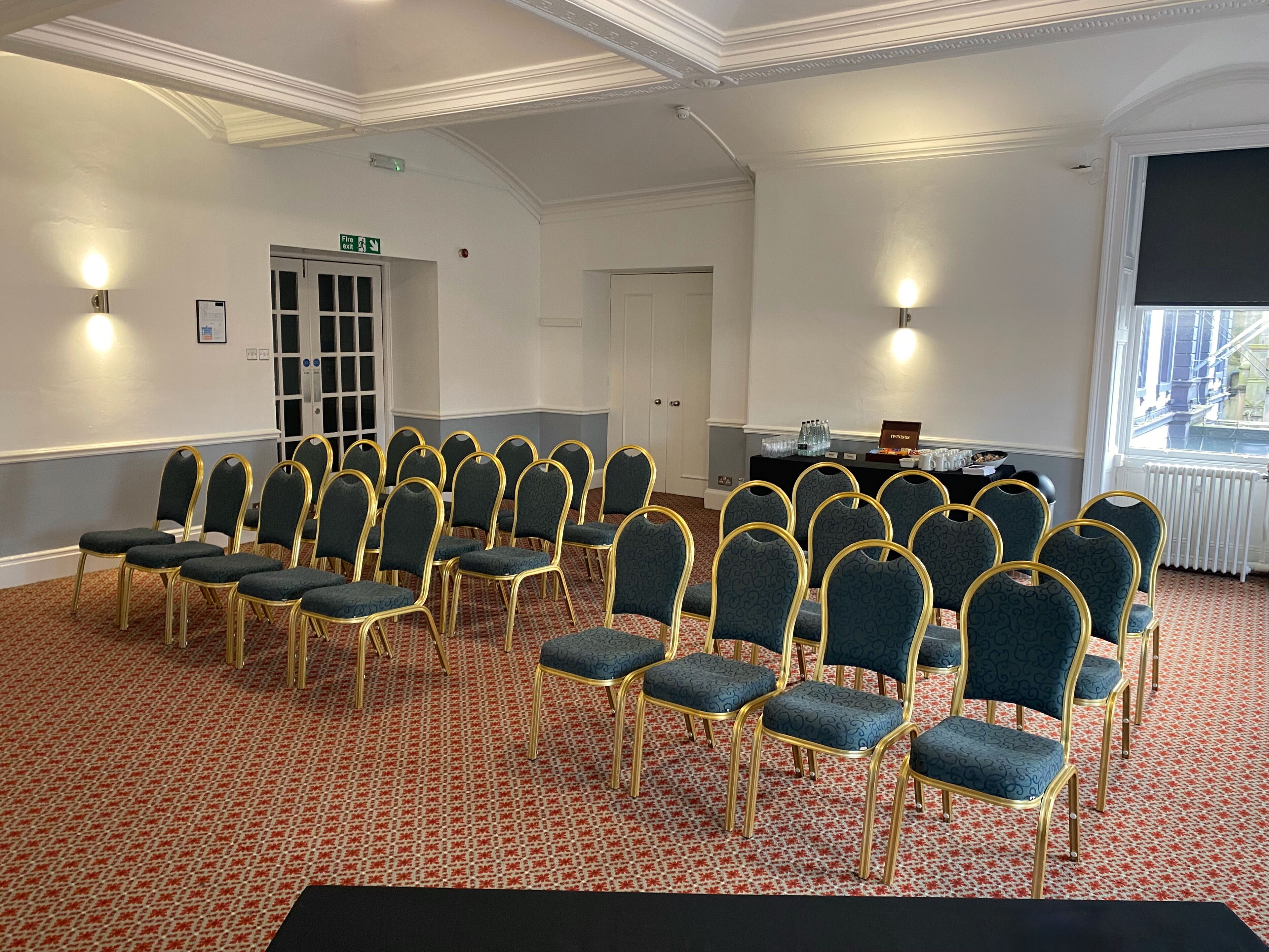 A conference room with rows of chairs, a black table with a nameplate, and a window with a view.