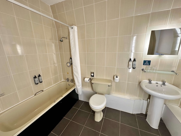 A bathroom with a bathtub, toilet, sink, and a shower area.