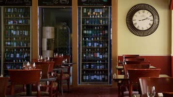 A bar area with wooden chairs and tables, shelves of liquor bottles, and a wall clock.