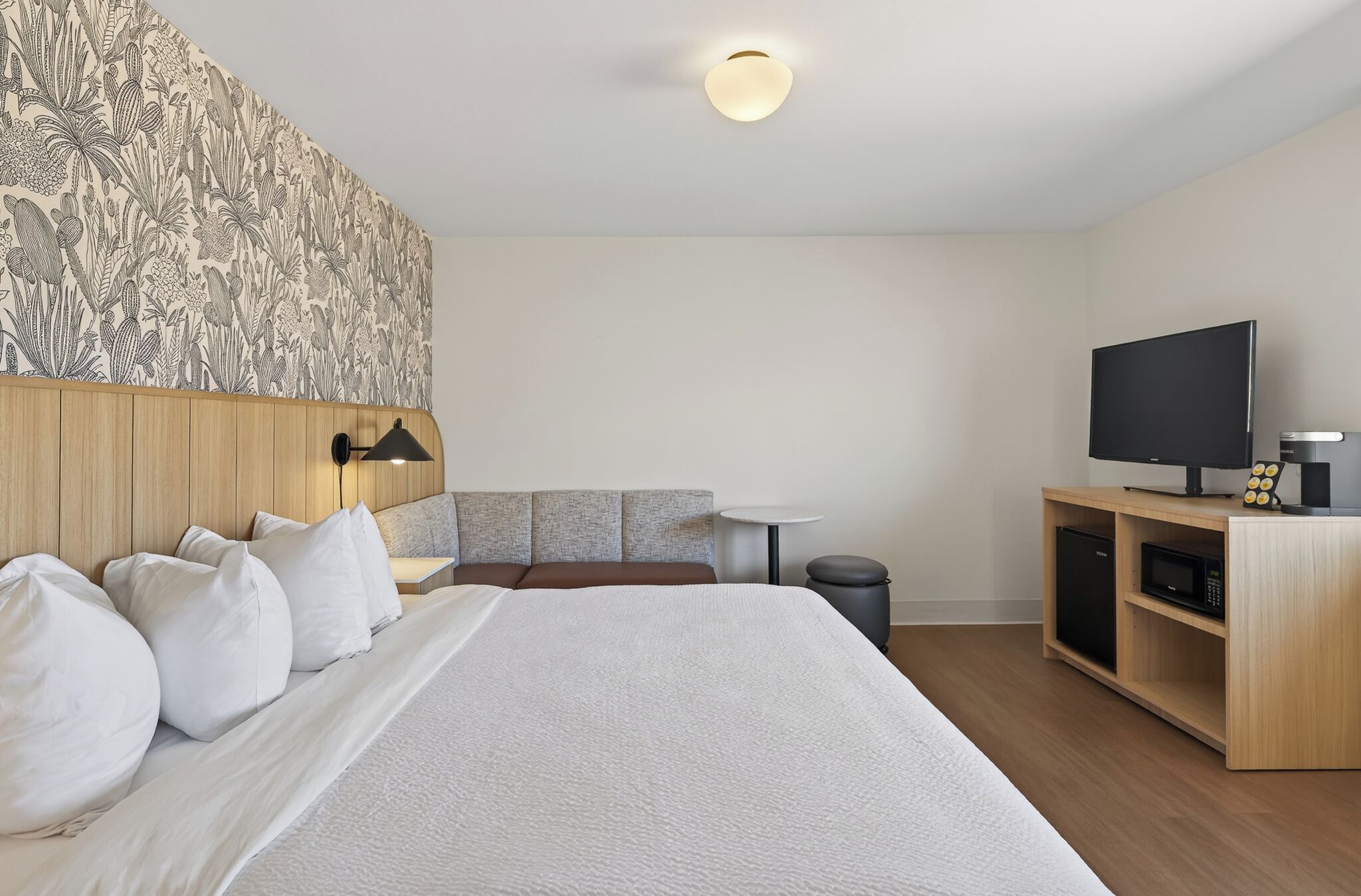 Een hotelkamer met een bed, een televisie, een kleintje tafeltje en een kast.