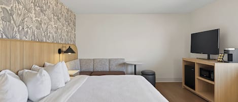 Une chambre d’hôtel avec un lit, une télévision, une petite table et un placard.