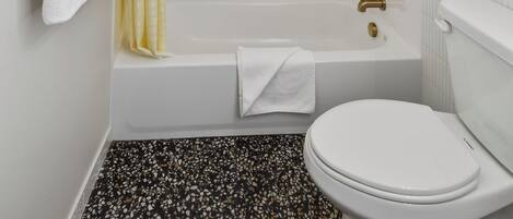A bathroom with a bathtub, toilet, and shower curtain.