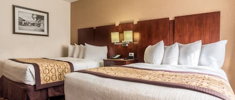 A hotel room with two beds, a nightstand with a phone, and a framed picture on the wall.