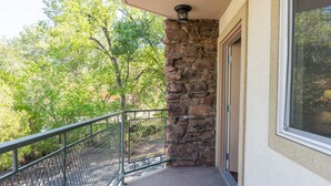 A balcony with a stone wall, metal railing, and a door leading to a covered area.
