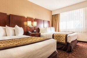 A hotel room with two beds, a wooden headboard, bedside lamps, a telephone, and a large window with sheer curtains. - Hotel Moab Downtown (Moab)