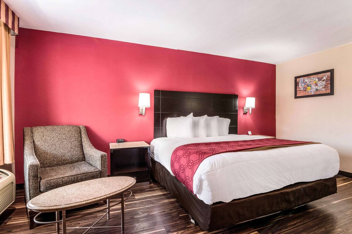 Una habitación de hotel con una cama grande, una silla, una mesita y una mesita de noche.