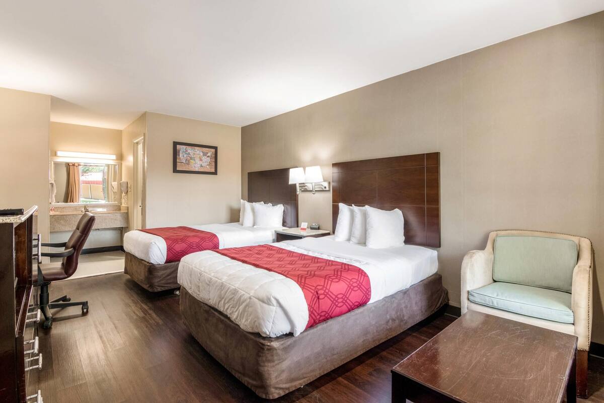 Habitación de hotel con dos camas, un escritorio, una silla y un sofá.