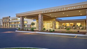 En hotellbyggnad som tillhör Delta Hotels-kedjan, en del av Marriott, med en modern fasad, ståtliga stenkärnor och en väl upplyst entré.