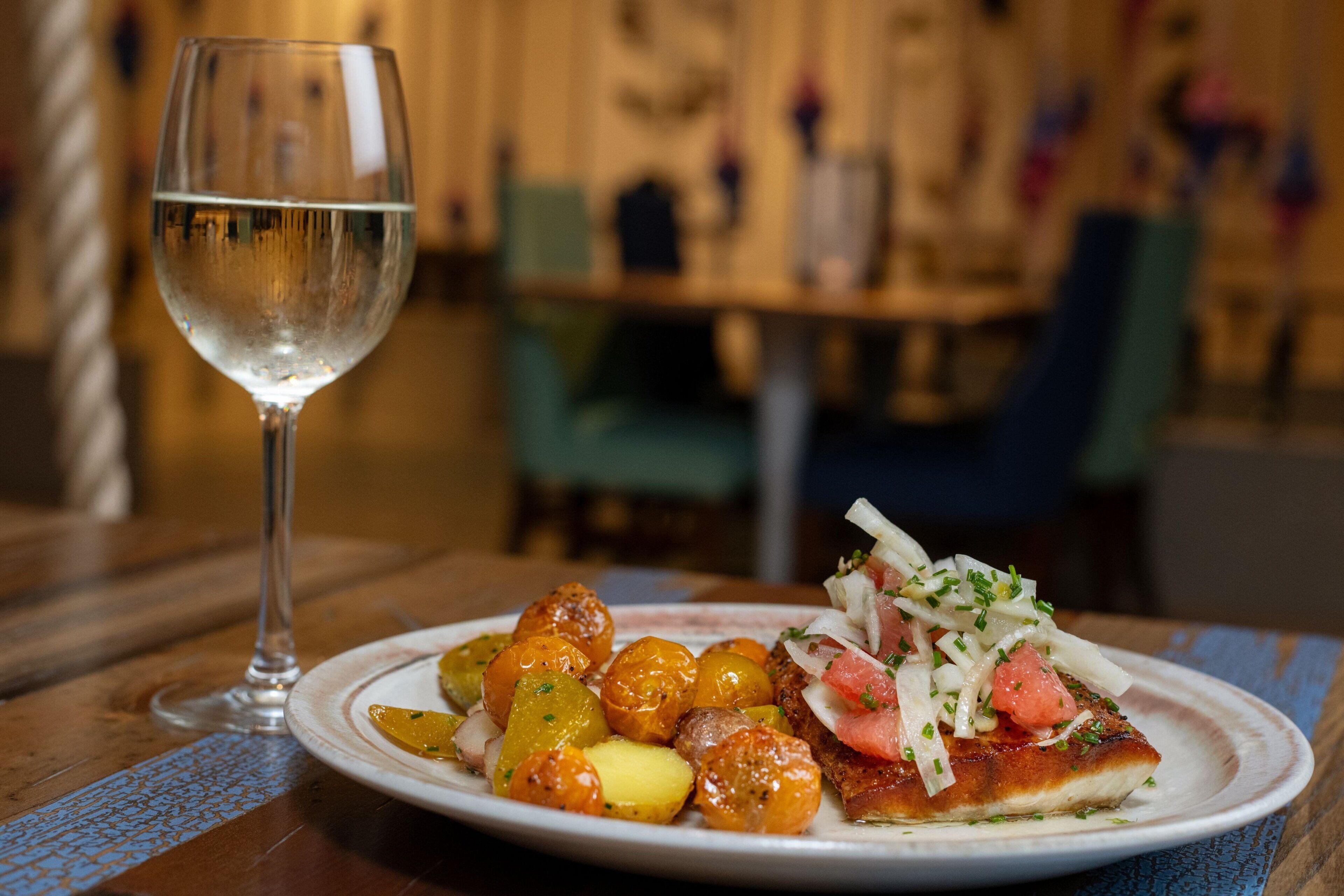 Ein Teller mit Essen und ein Glas Wasser auf einem Holztisch.