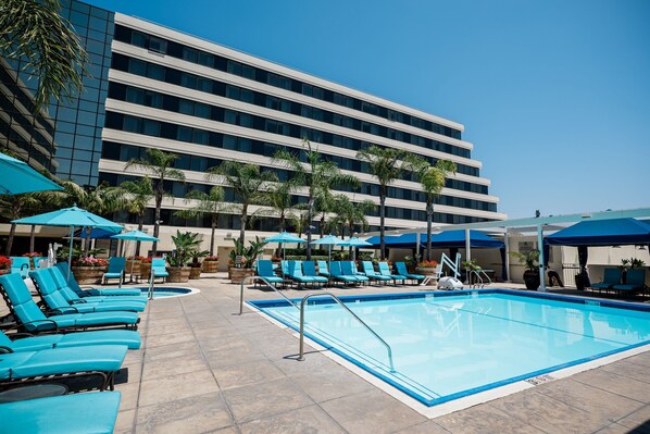 Una piscina al aire libre, camas de piscina con cargo, sombrillas