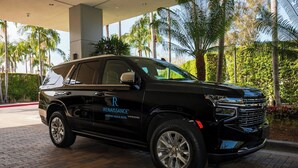 Un SUV nero parcheggiato all'ingresso di un hotel, con palme sullo sfondo.
