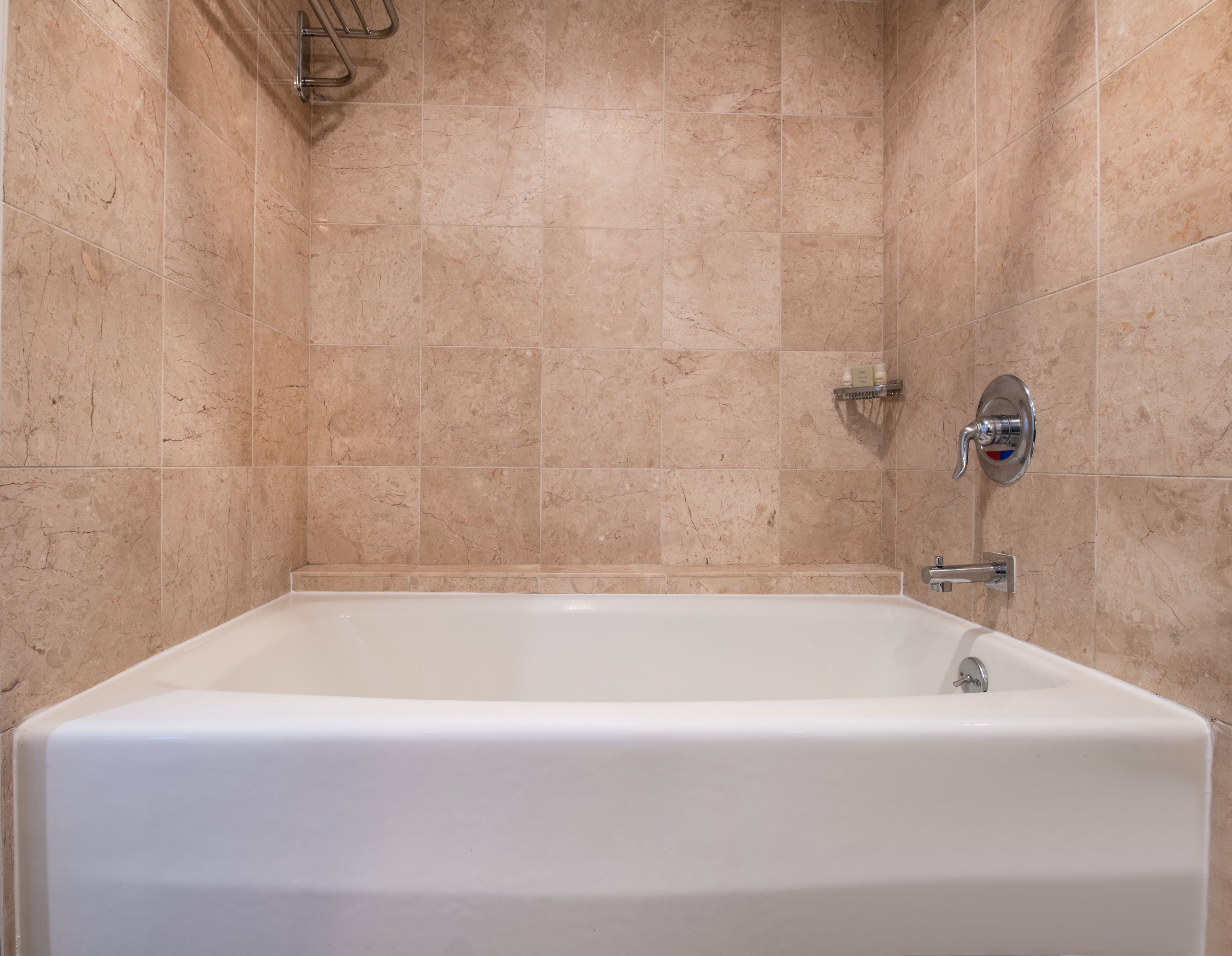 A modern bathroom with a freestanding bathtub, a handheld showerhead, and a wall-mounted faucet.