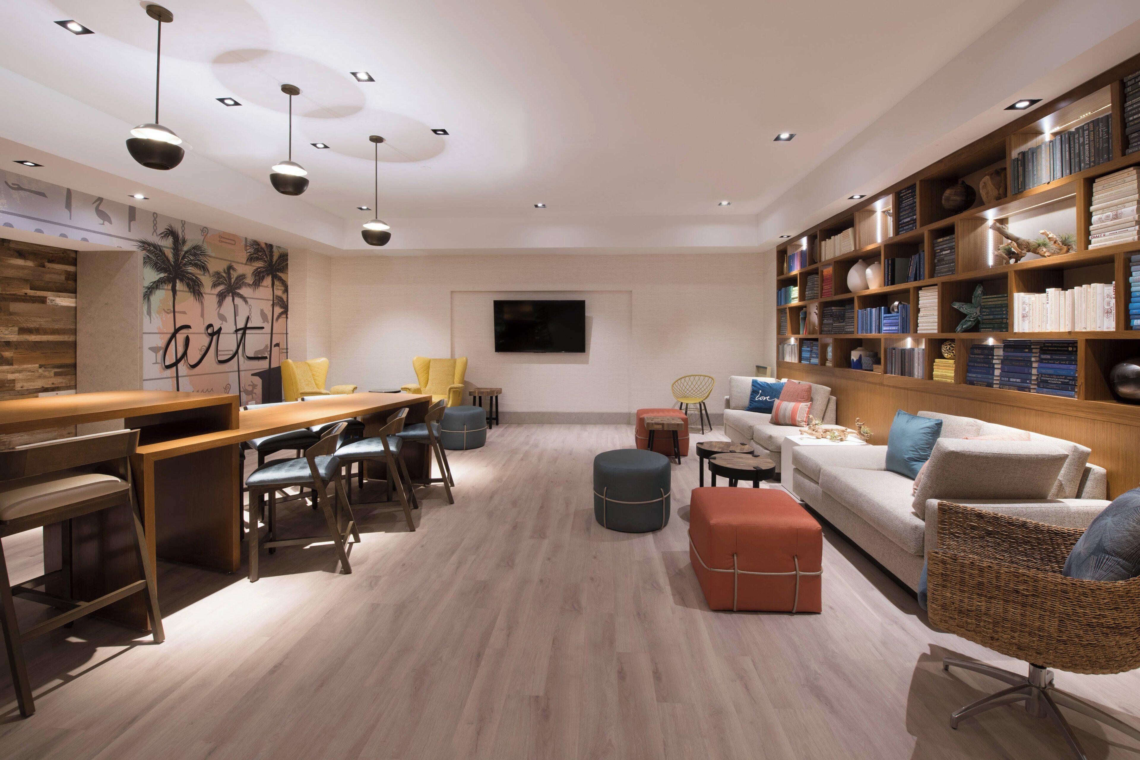 Een moderne woonkamer met een houten bureau, comfortabele zitplaatsen, een boekenkast en een flatscreen televisie.