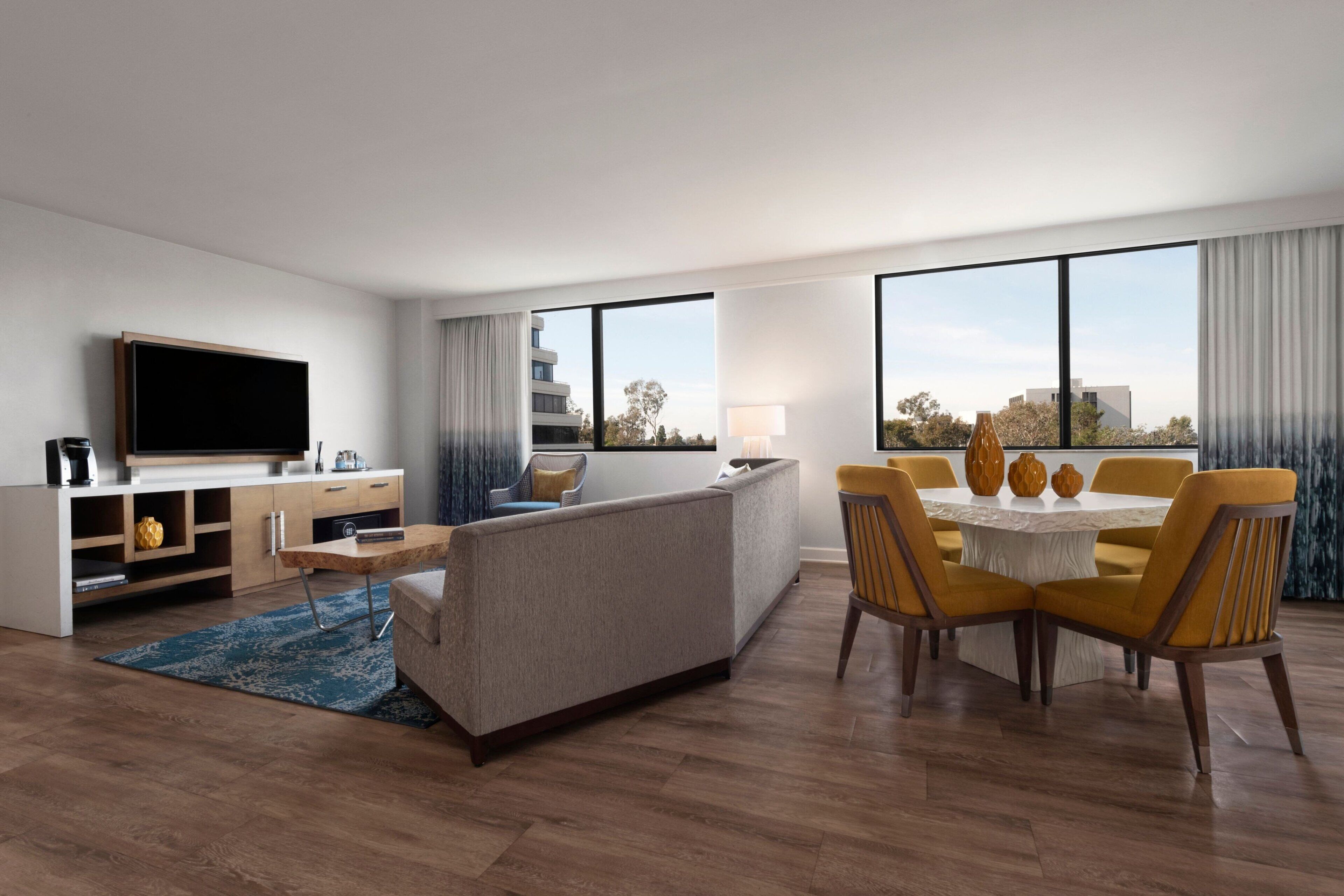 A modern living room with a sofa, TV, dining table, and chairs.