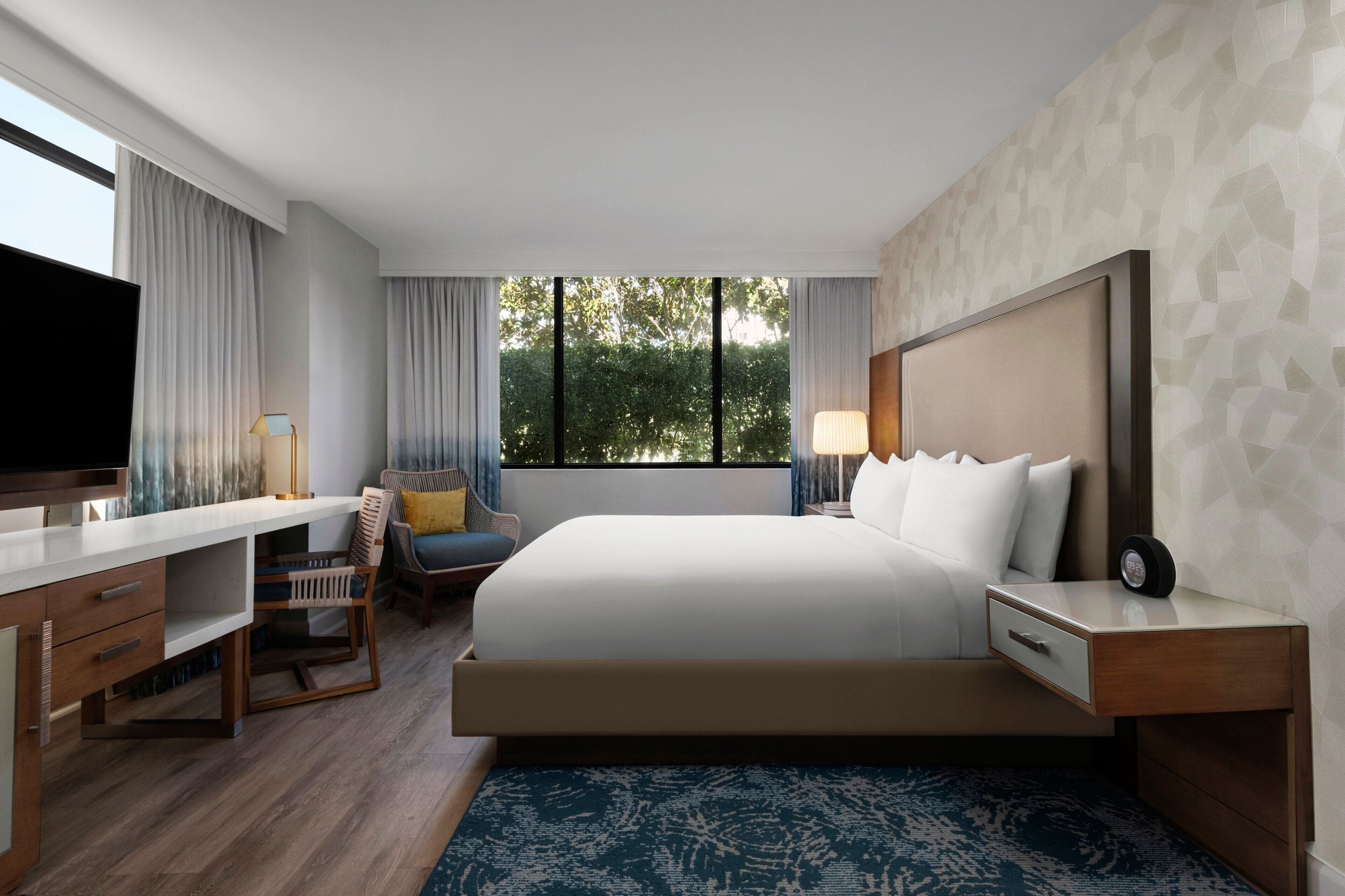 Une chambre d’hôtel moderne équipée d’un grand lit, d’un bureau, d’une chaise et d’un téléviseur.