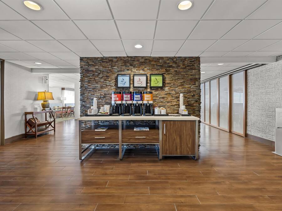 Eine moderne Kaffeestation mit Backsteinwand, gerahmten Kunstwerken und verschiedenen Kaffeesorten.