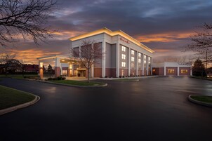 Un hotel moderno con una entrada espaciosa, una zona de estacionamiento bien iluminada y un cielo despejado.