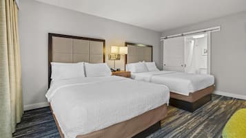Habitación de hotel con dos camas, una mesita de noche, una lámpara, un espejo y una puerta corredera.