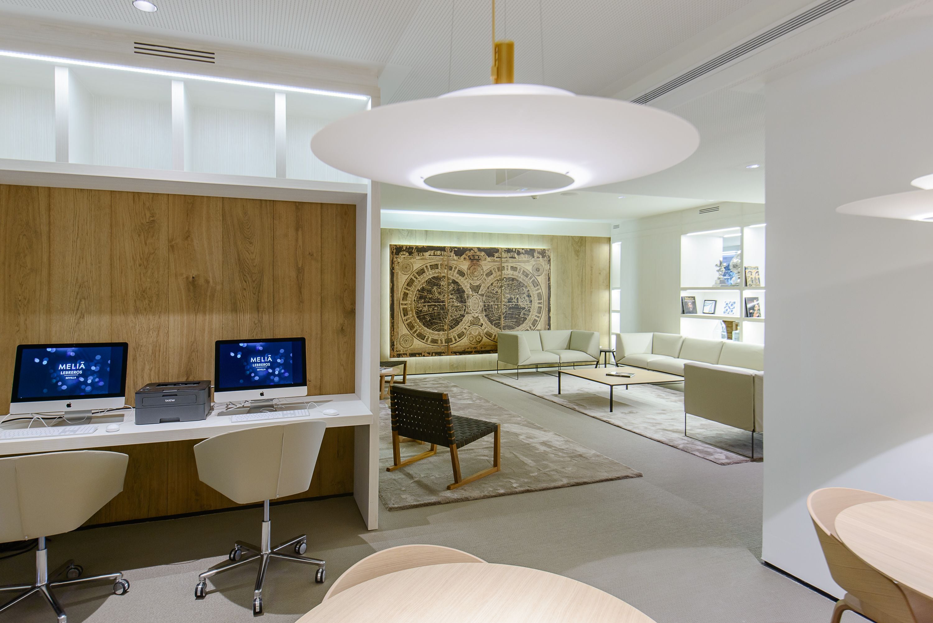 Un espace de bureau moderne comprenant deux bureaux, des chaises et un grand mur décoratif.