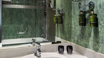 A modern bathroom with a glass-enclosed shower, a large mirror, and a sink with two black cups.