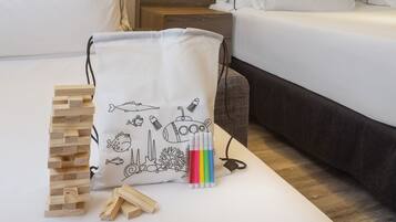 A bed with white bedding, a white pillow with a drawing of a submarine and other sea creatures, and a set of wooden blocks and colorful markers on the floor.