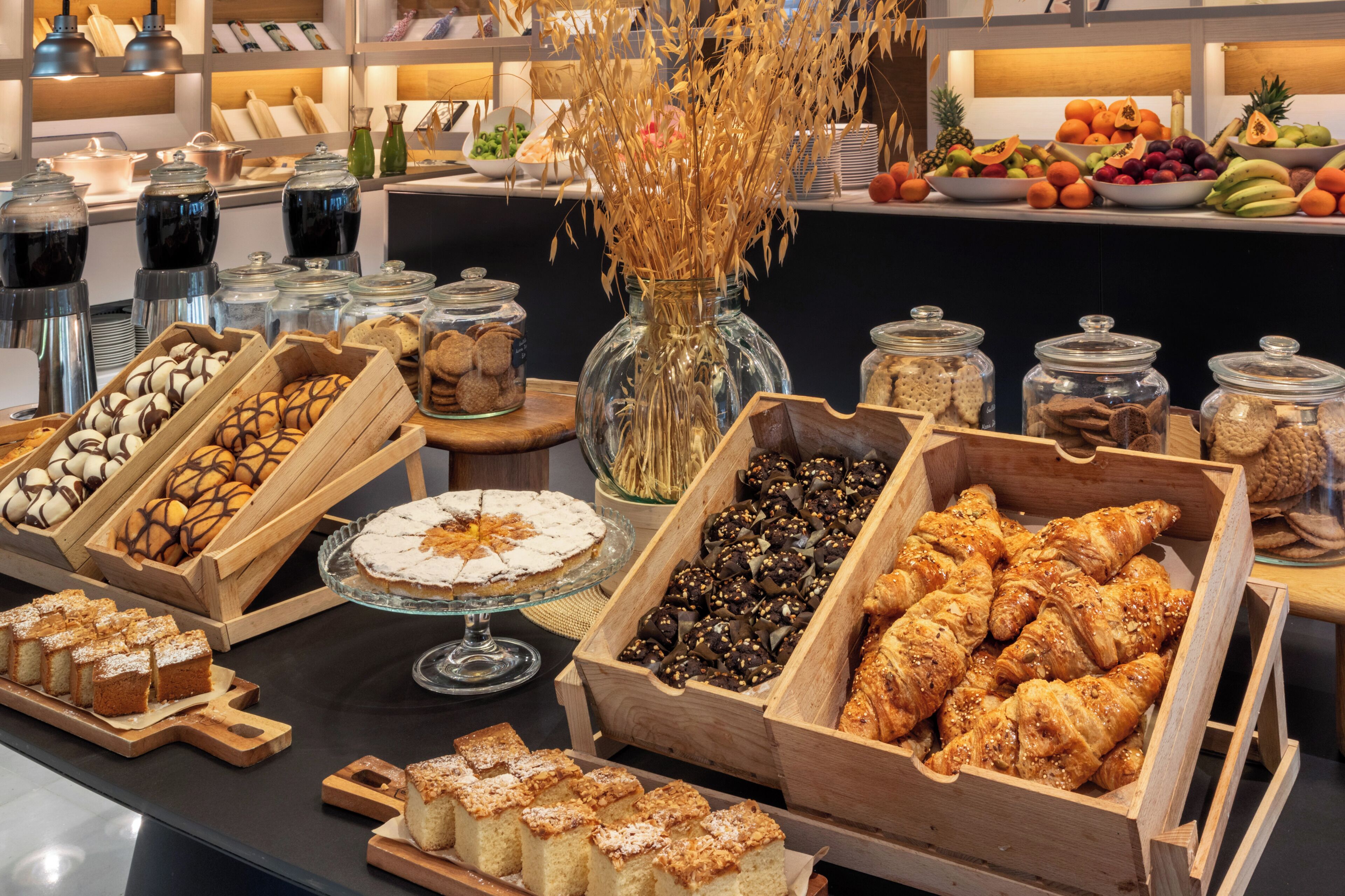 A buffet with various food items, including pastries, fruits, and desserts.