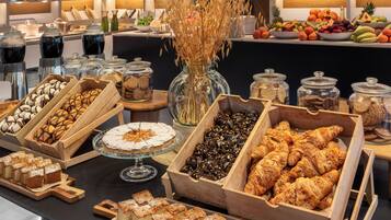 A buffet with various food items, including pastries, fruits, and desserts.