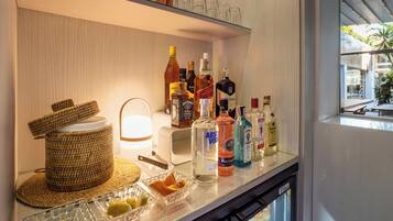 A bar area with a glass shelf holding various bottles, a woven basket, and a lit lamp.