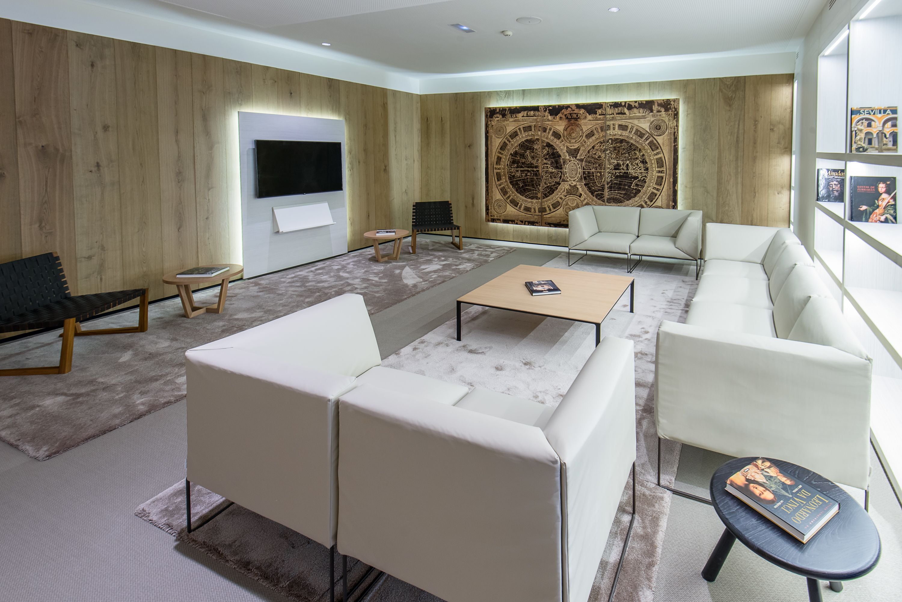 A modern living room with a flat-screen TV, a large tapestry, and a seating area with sofas and a coffee table.